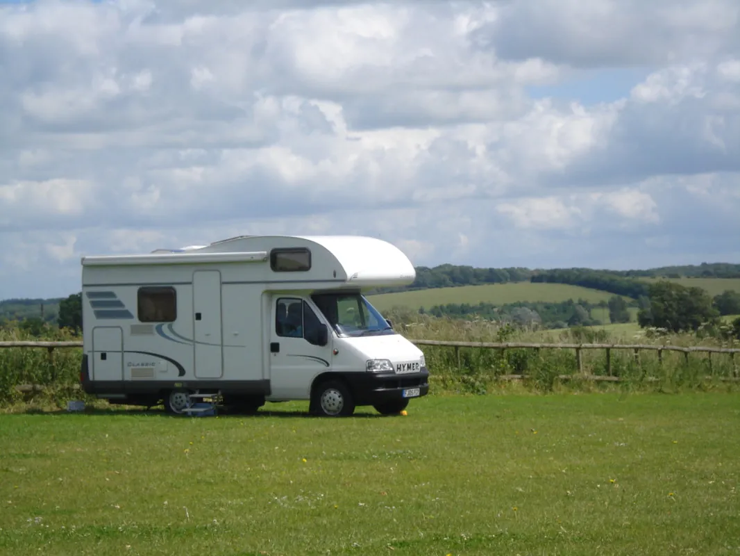 A motorhome pitched on the grass campsite with views over the countryside