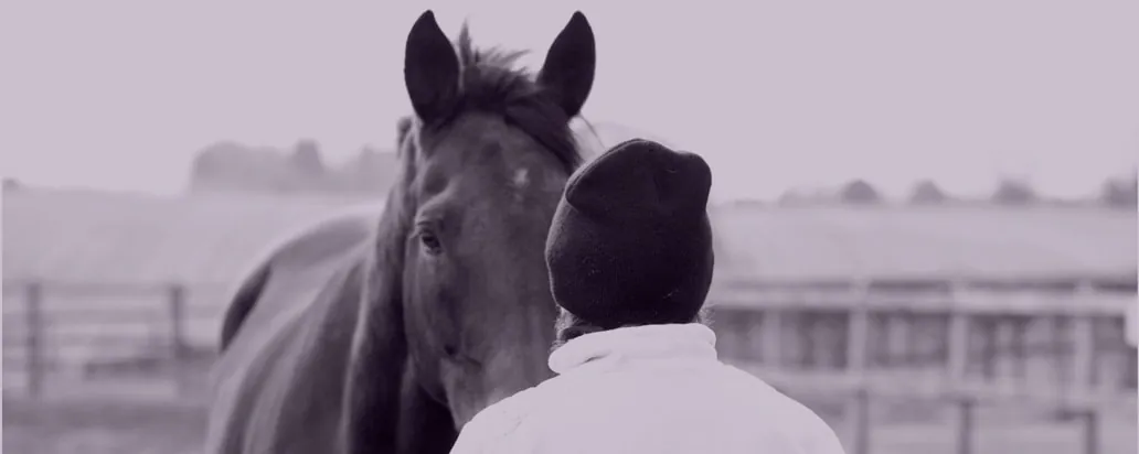 A horse and a person in a hat, side by side, in a black and white photo