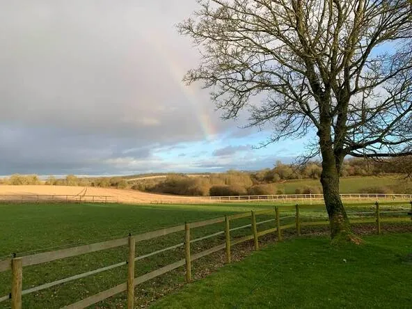 Post and rail paddocks under a rainbow